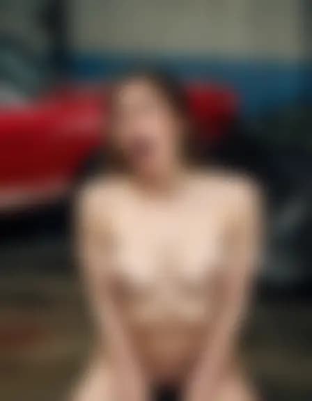 Abigail enjoys a moment of pleasure amidst a vintage Mustang and hydraulic lift.