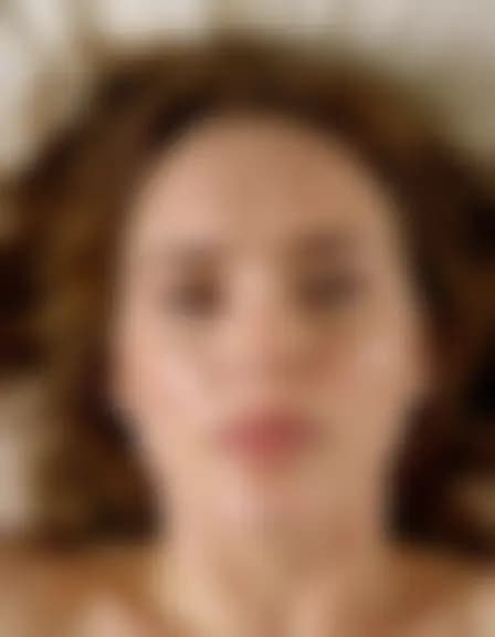 Zoe enjoying a facial cumshot in a messy bedroom.