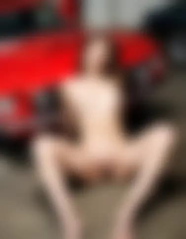 Abigail enjoys a moment of pleasure amidst a vintage Mustang and hydraulic lift.